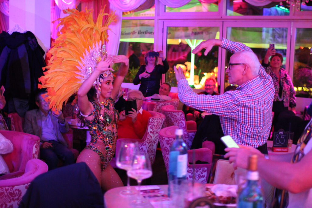 Berlin Variety Show for tourists at weekend is the perfect answer to the question “What to do in Berlin at night?” when you want more than just a bar or a basic dinner. The Berlin Variety Show for tourists at weekend at Wilde Matilde in the Nikolaiviertel delivers a full 4-hour night out with singers, dancers, aerial artists, burlesque and live saxophone or violin every Friday and Saturday from 7 pm. Berlin Variety Show for Tourists at Weekend in the Nikolaiviertel The Berlin Variety Show for tourists at weekend takes place in Wilde Matilde, a colorful 1920s-inspired variety restaurant and cocktail bar right in Berlin Mitte, just a short walk from Alexanderplatz and the TV Tower. Surrounded by the historic streets of the Nikolaiviertel with views of the Berlin Cathedral and the City Palace, visitors enjoy a show night in one of the most atmospheric corners of the city. 4 Hours of Non-Stop Entertainment During the Berlin Variety Show for tourists at weekend, the stage, carousel bar and even the room itself turn into a playground for artists for around four hours. Guests experience a changing programme with singers, dancers, aerial acrobats, magicians, jugglers, burlesque performers, comedy acts and live musicians on saxophone or violin, so there is always something happening. Perfect Answer to “What to Do in Berlin at Night?” For anyone searching “what to do in Berlin at night” or “shows near Alexanderplatz”, the Berlin Variety Show for tourists at weekend offers the complete package in one location. Instead of having to plan separate dinner, bar and entertainment stops, visitors simply book a table at Wilde Matilde and get food, drinks and show under one roof. Cocktails at the Carousel Bar During the Show A special highlight of the Berlin Variety Show for tourists at weekend is the unique carousel bar in the middle of Wilde Matilde, decorated with rococo chairs, bright colors and nostalgic fairground details. While the show unfolds around and above them, guests sip creative cocktails, gin specials and long drinks as dancers and candy girls use the bar as a stage. German Cuisine and Sweet Treats Included The Berlin Variety Show for tourists at weekend can be enjoyed with a full dinner or snacks from the in-house kitchen, which serves German and Berlin classics throughout the evening. There is also a patisserie with homemade cakes, tarts and desserts, so visitors can combine the show with savoury dishes and sweet temptations for a complete night out. Ideal Weekend Plan Near Alexanderplatz Because the Berlin Variety Show for tourists at weekend starts at 7 pm every Friday and Saturday, it fits perfectly after sightseeing at Alexanderplatz, the TV Tower, Museum Island or the nearby Christmas markets in season. Tourists can explore Berlin during the day and then head to the Nikolaiviertel in the evening for an all-in-one show experience just a few minutes’ walk from the main transport hub. Great for Couples, Friends and Groups The Berlin Variety Show for tourists at weekend is suitable for couples, friends, hen parties, birthdays, company outings and travel groups, with reserved tables and different ticket and menu options. Thanks to the colourful décor, costumes and lively atmosphere, the show also provides plenty of photo opportunities and memories that go far beyond a normal restaurant visit. How to Book Tickets for This Weekend To secure seats for the Berlin Variety Show for tourists at weekend, visitors should reserve in advance via the Wilde Matilde ticket or reservation page, especially for Friday and Saturday evenings which sell out quickly. Last-minute guests can sometimes still find remaining capacity, but anyone who wants a guaranteed table close to the carousel bar and stage is well advised to book now for this weekend. The Berlin Variety Show for tourists at weekend at Wilde Matilde gives you the full Berlin night: variety theatre, live music, burlesque, cocktails and German cuisine in one colourful venue near Alexanderplatz. If you are still wondering what to do in Berlin at night, this is your sign to grab tickets for the Berlin Variety Show for tourists at weekend and turn your city trip into an unforgettable show experience.